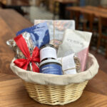 2022 holiday gift basket at republique, featuring granola, coffee, jam, cookies, cocoa mix, scone mix, and a cookbook in a round wicker basket